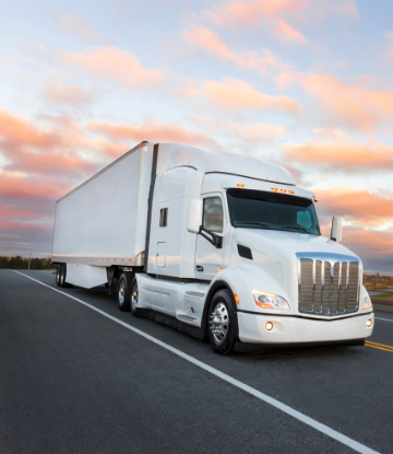 Image of an 18-wheel truck driving on highway at sunset