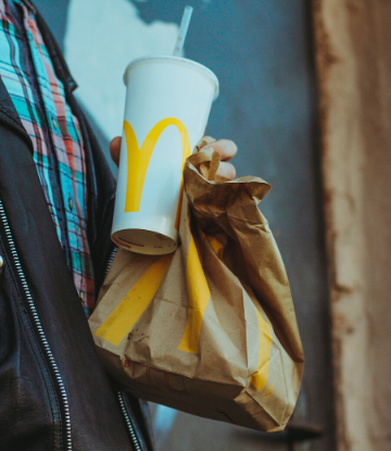 Close up image of a person holding a drink with a McDonald's food bag