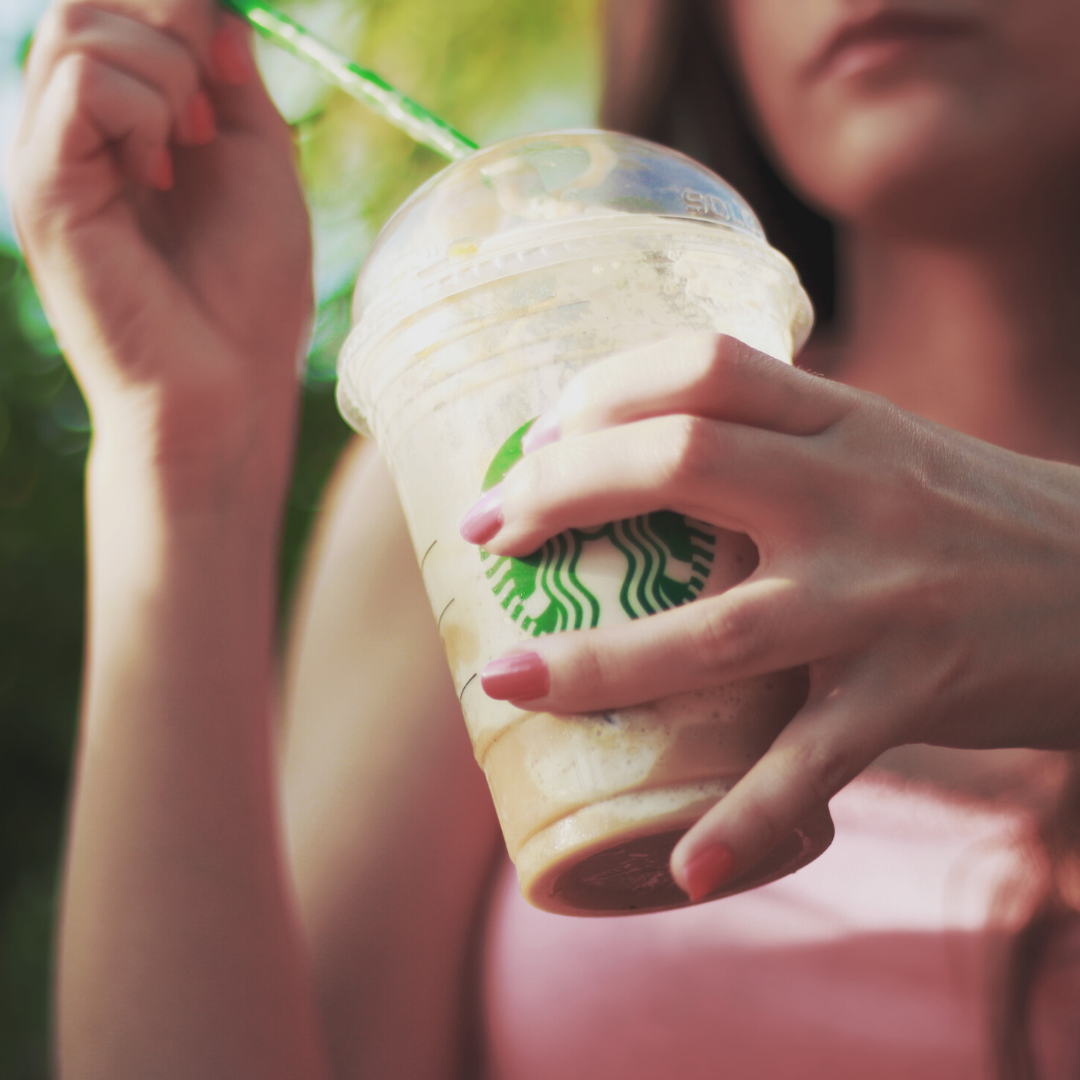 Image of a woman holding a starbucks cold drink cup with a straw 