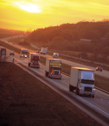 SCS, image of large trucks on the highway at sunset