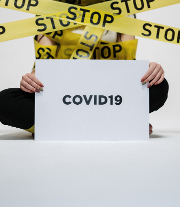 SCS, imag of caution tape over a person holding a COVID19 sign 