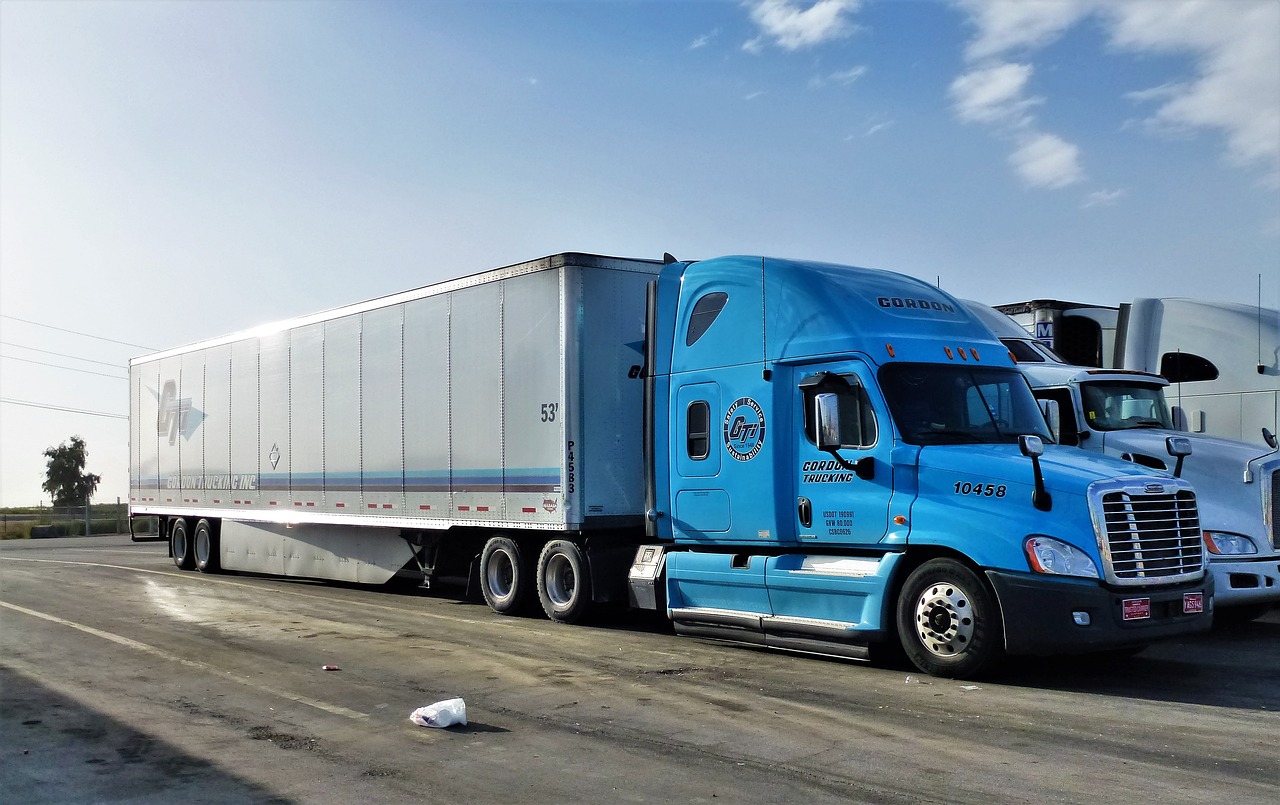 Blue semi truck with blue sky above.