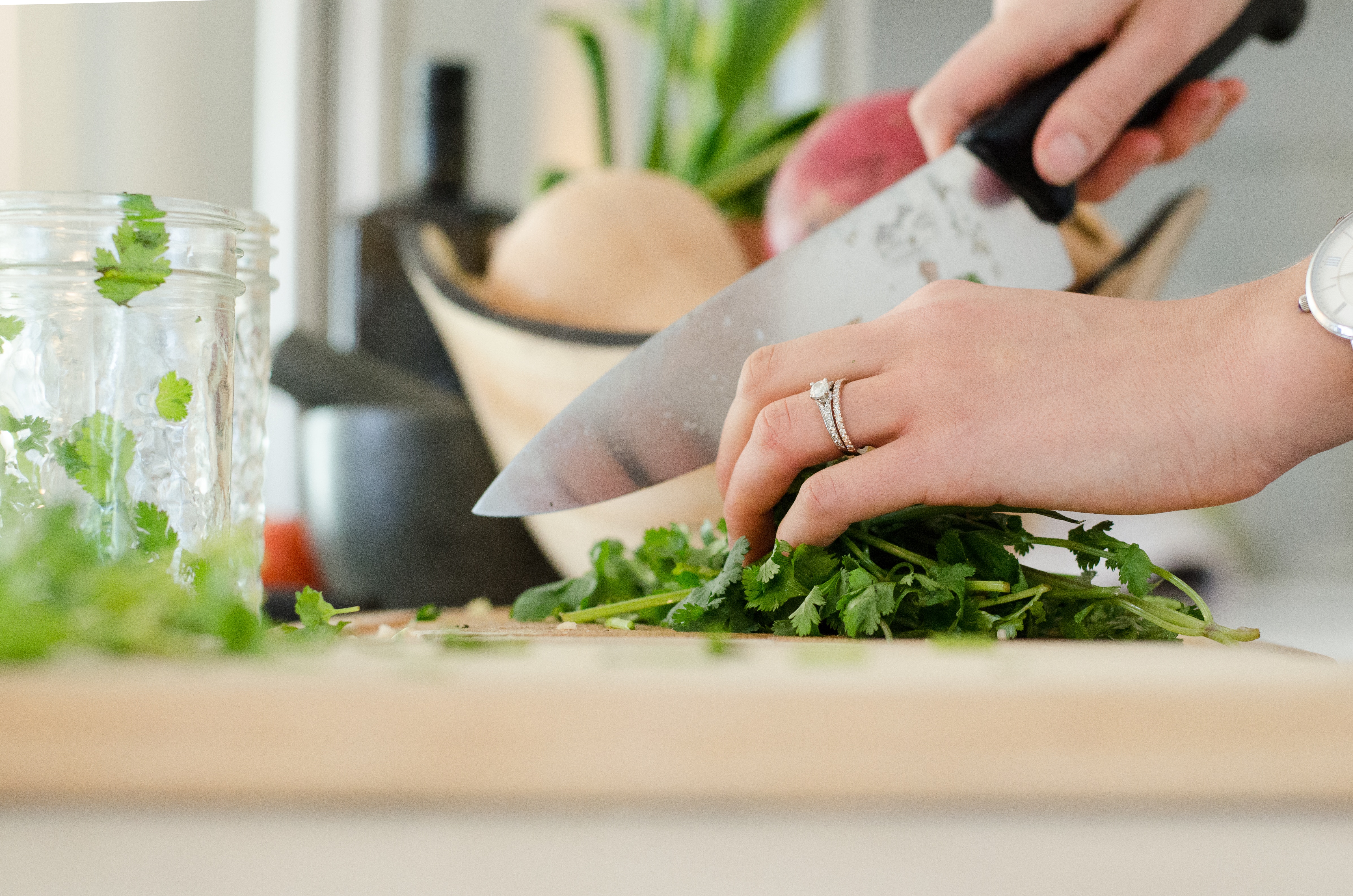 Hands of woman chopping herbs on cutting board