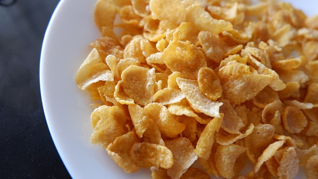 A white bowl of corn flakes with milk.