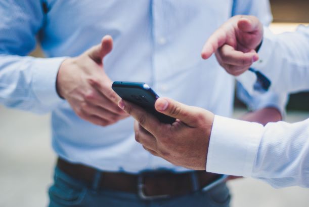 Men's hands pointing at cell phone.