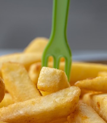 French fries with small green fork and grey background