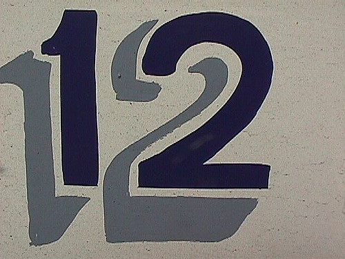 The # 12 painted on concrete in black and dark grey