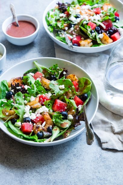 Two bowls of salad with dressing on the side