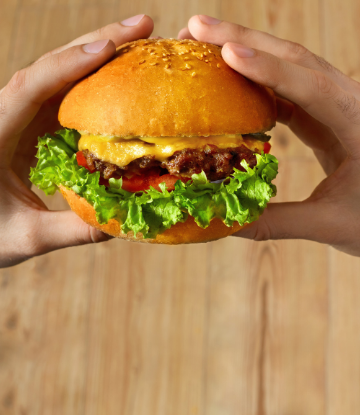 Supply Chain Scene, image of two hands holding a burger about to take a bite