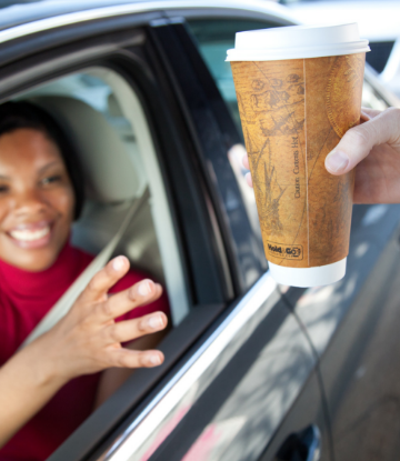 Supply Chain Scene, image of a woman at a drive thru reaching for a disposable drink cup