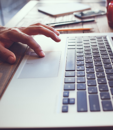 Supply Chain Scene, close up image of a hand on a Macbook computer 