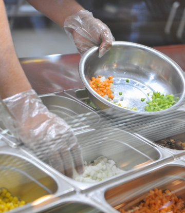 Supply Chain Scene, image of a foodworker wearing gloves and handling food