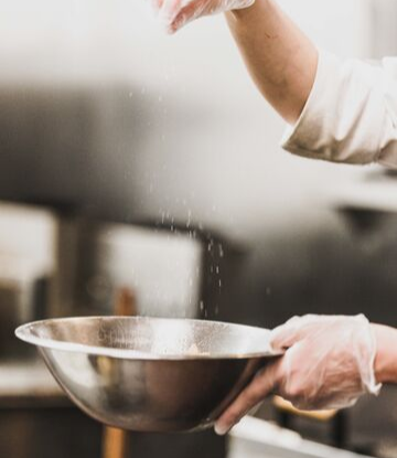 Supply Chain Scene, image of a cook in a restaurant kitchen, with a stainless steel bowl