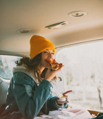 Supply Chain Scene, image of a person in a car eating a slice of pizza 