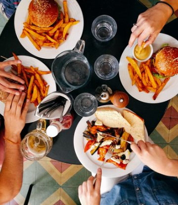 SCC, overhead image of 4 plates of food with hands showing people eating from them 