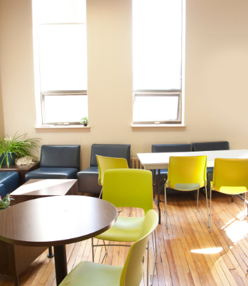 Image of empty tables and chairs in an open, sunny room 