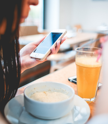 SCS image of a youngwoman eating oatmeal with orange juice drink at a restaurant