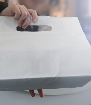 SCS, image of a hand holding a white paper food bag 