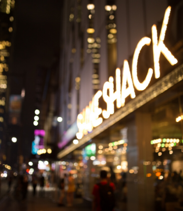 SCS, bluured image of a shake shack store front at night, in a major city 