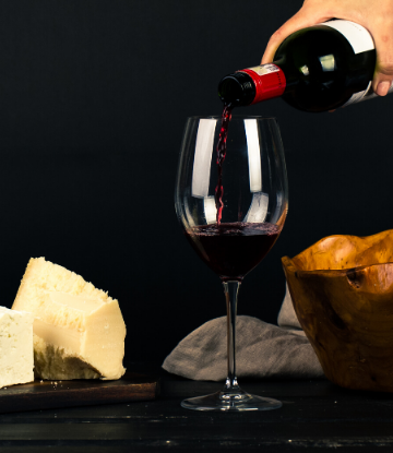 SCS, image of a glass of red wine being poured next to fine cheese wedges 