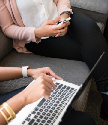 SCS, image of 2 women on iphone and laptop 