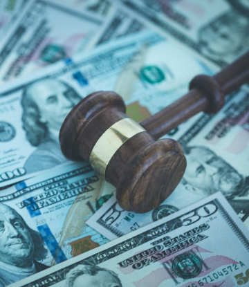 Image of a pile of money with a judge's gavel on top