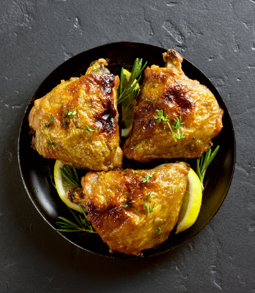 Image of a plate of generic, fried chicken thighs with a lemon slice 