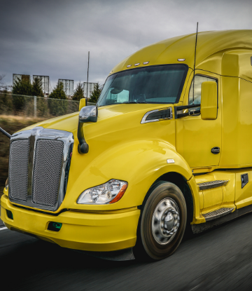 Image of the cab of a bright yellow truck on the road 